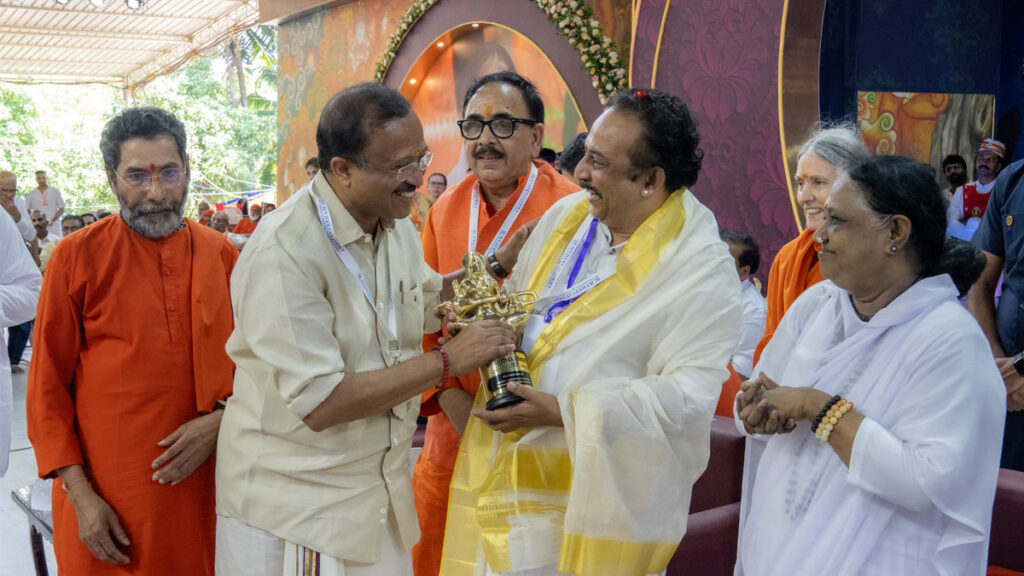 Amma smiles as a man is given a golden statue of Sarsaswati 