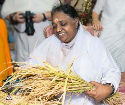 Amma holds grains in her hands and smiles