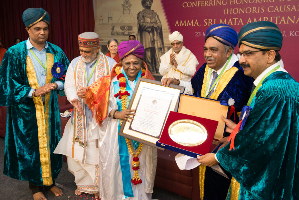 Amma and dignitaries holding the awards while standing on stage