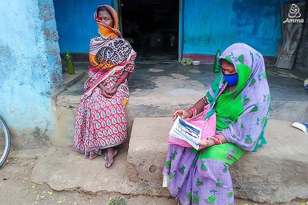 a health worker with a woman, both faces covered and covid distance between them