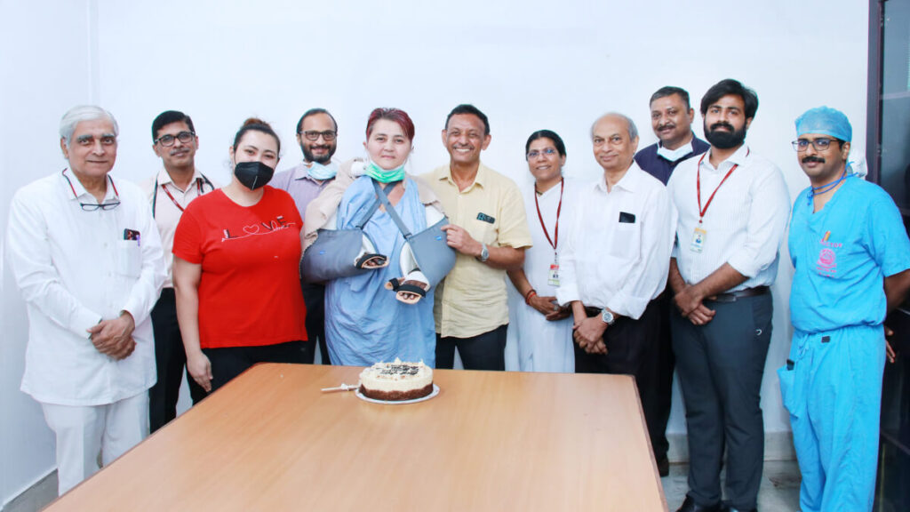 Gulnora with her medical team standing in front of cake with lit candles ready to celebrate a successful surgery.