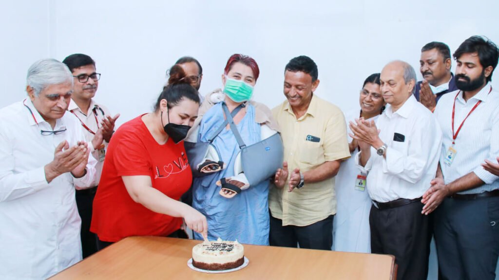 One of the medical team cuts the celebratory cake while the rest of the team and Gulnora watch with smiles on their faces.