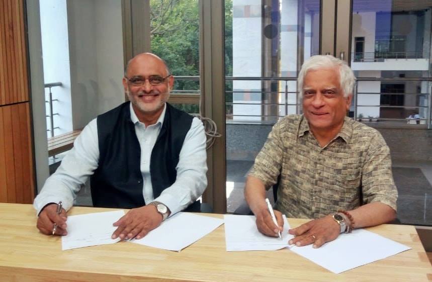 Dr. Bipin Nair and Professor Suresh Subramani seated at a table signing papers.