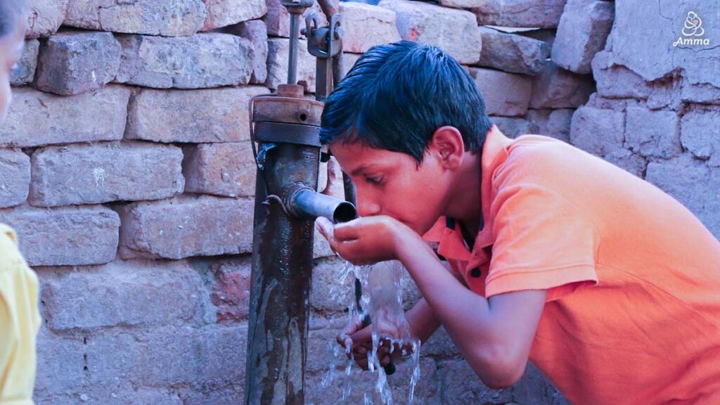 a boy drinks water at a village tap