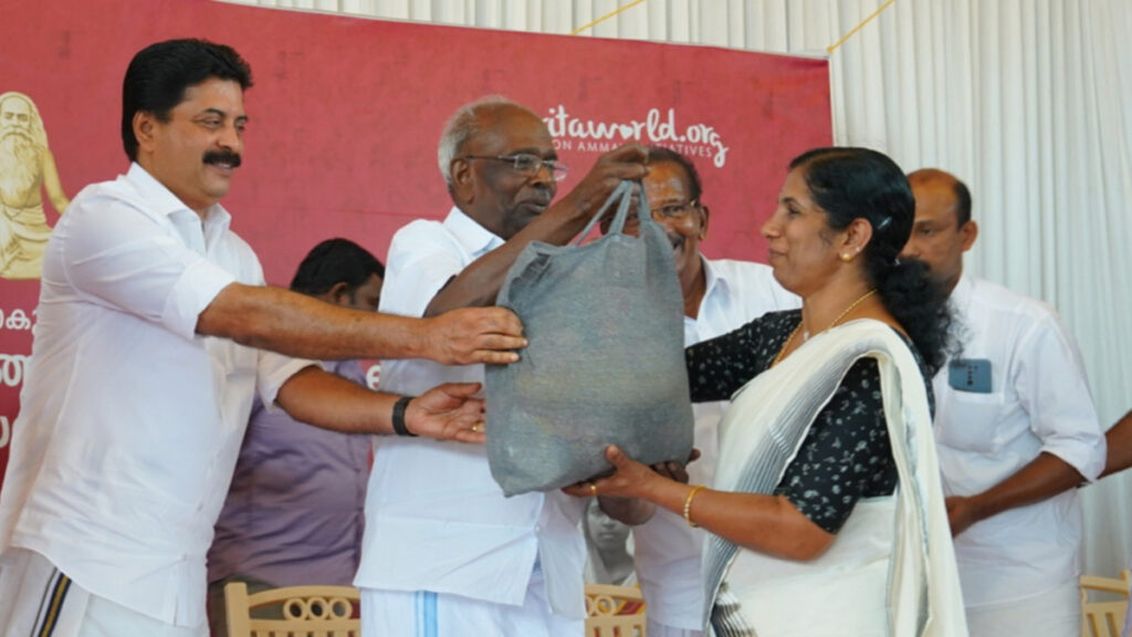 MM Mani, Kerala MLA (CPIM), hands a bag of supplies to a SGH member.