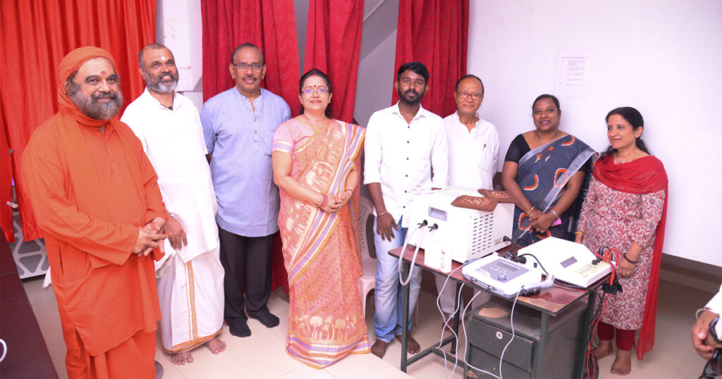 Swamiji and other volunteers stand and smile next to the new equipment