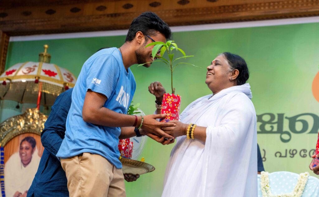 Amma blesses an AYUDH youth who is holding a sapling