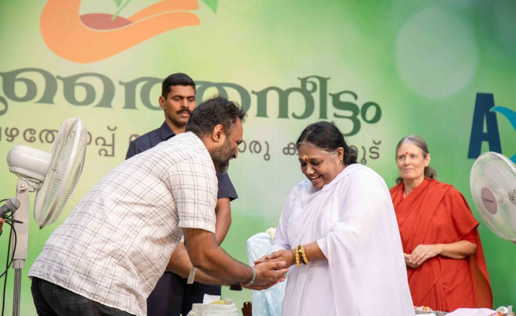 Amma passes seeds into the hand of a man