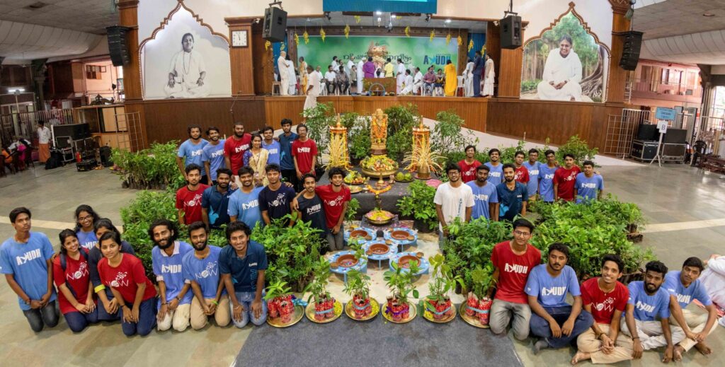 AYUDH members pose next to the plants in front of the stage