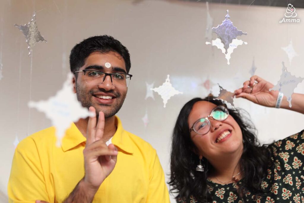 a young man and woman give the peace sign amidst cutouts of silver stars