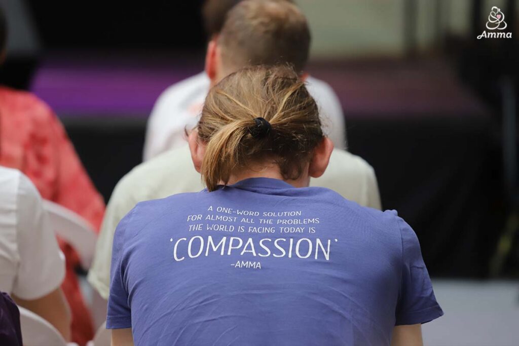 the back of a youth's t-shirt has a quote from Amma about compassion as a solution for most of the problems in the world