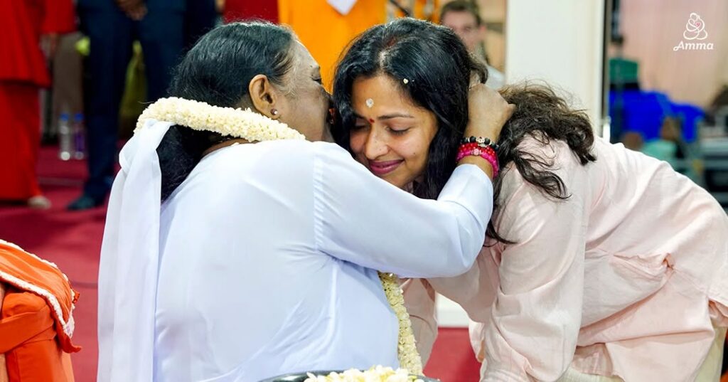 Amma embraces a woman