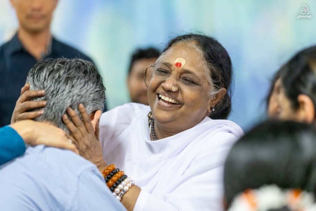 Amma comforts a man in a wheelchair