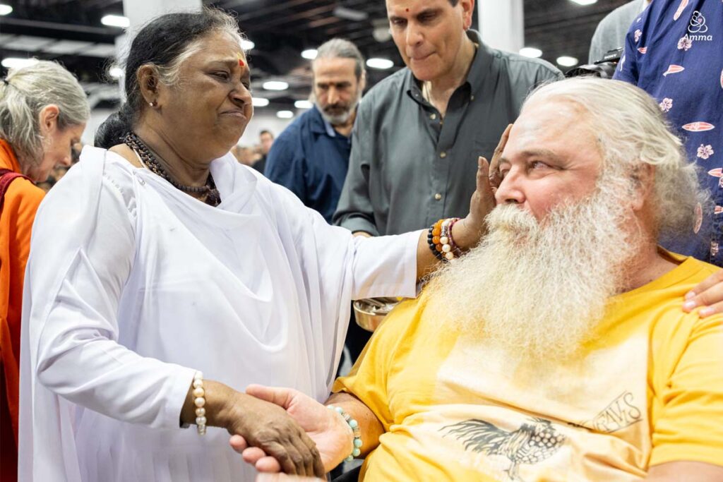 Amma comforts a man in a wheelchair