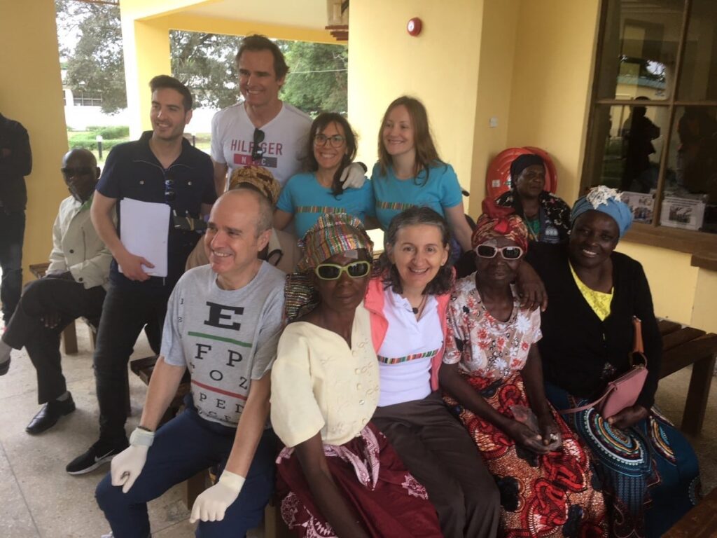 Team members and patients, some in dark glasses, sit together and smile. 