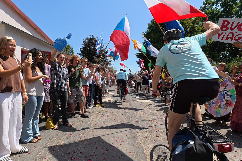a crowd cheers cyclists as they begin their journey
