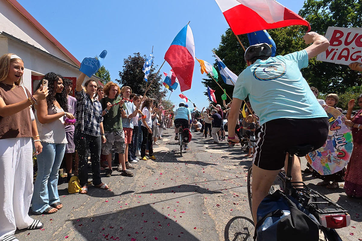 a crowd cheers cyclists as they begin their journey