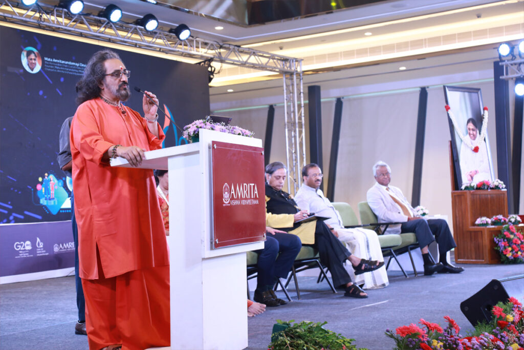 Swami Amritaswarupananda Puri at the podium addressing the importance of policy benefitting the students not harming them.