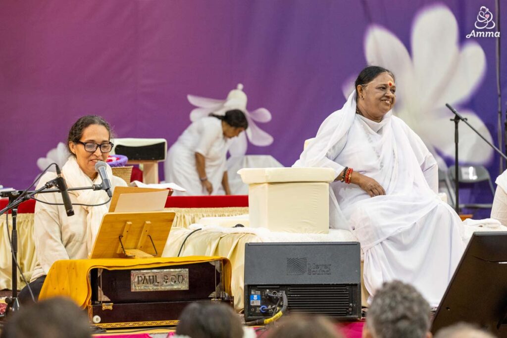 a woman speaks beside Amma