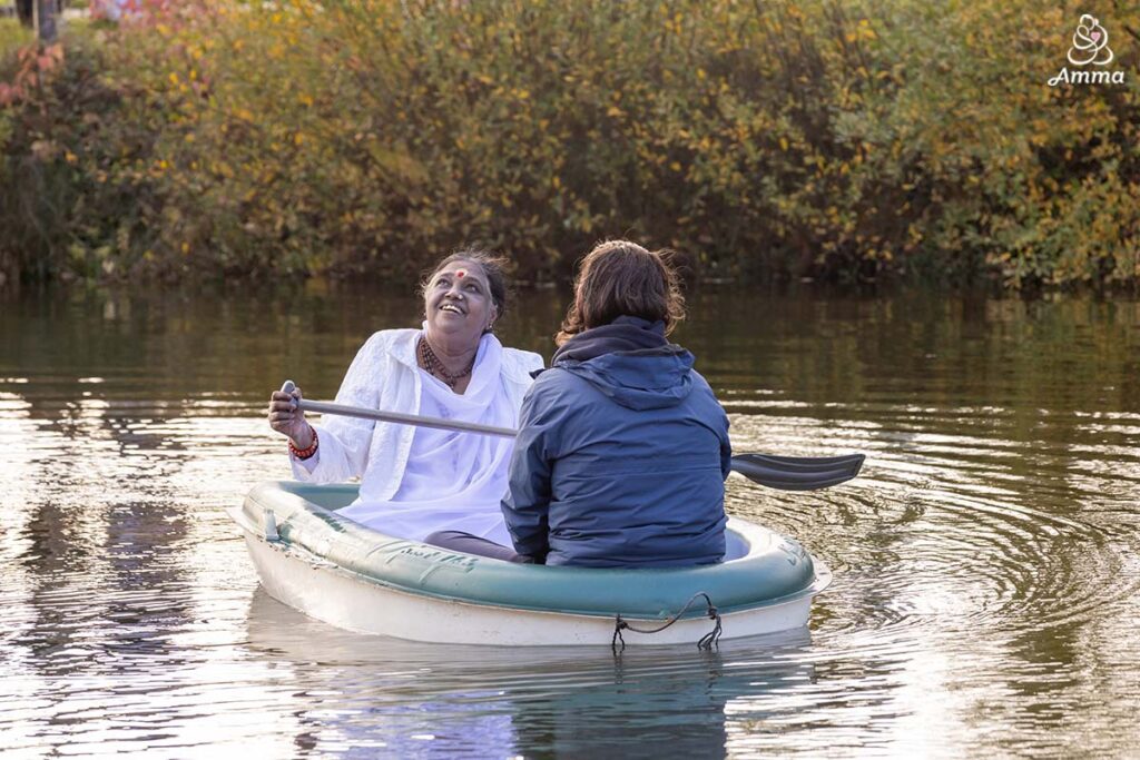 Amma rows a boat with a devotee