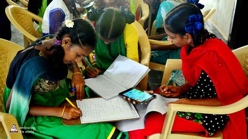 Young women sit and write in their notebooks