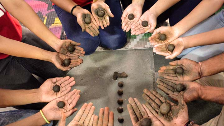 a circle of hands holding seedballs