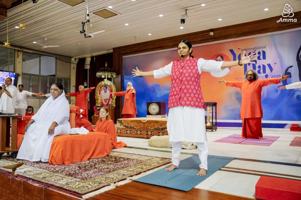 Amma watches a brahmacharini lead yoga instruction