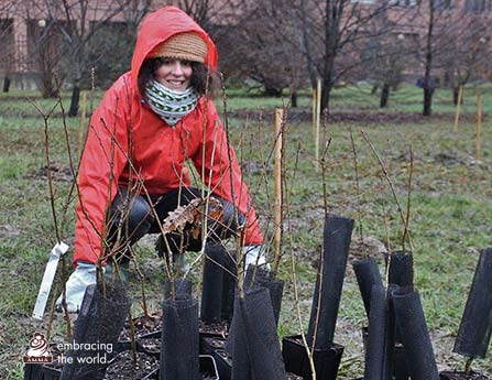 A woman with several small trees waiting to be planted