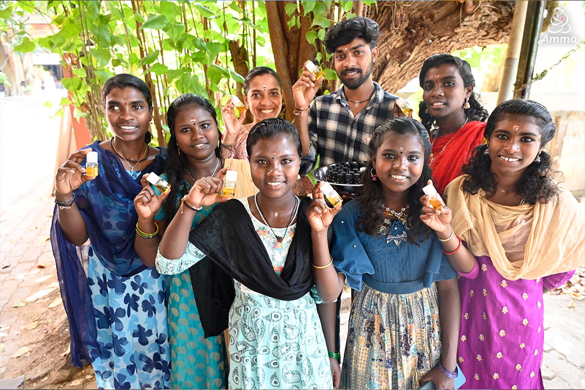 A group of seven young women hold up bottles of essential oil