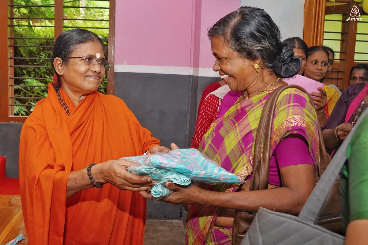 a Swamini gives a sari to a woman