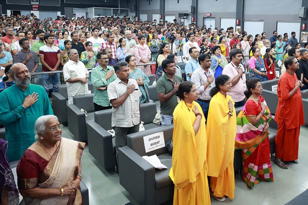 a crowd holds their hands over their hearts