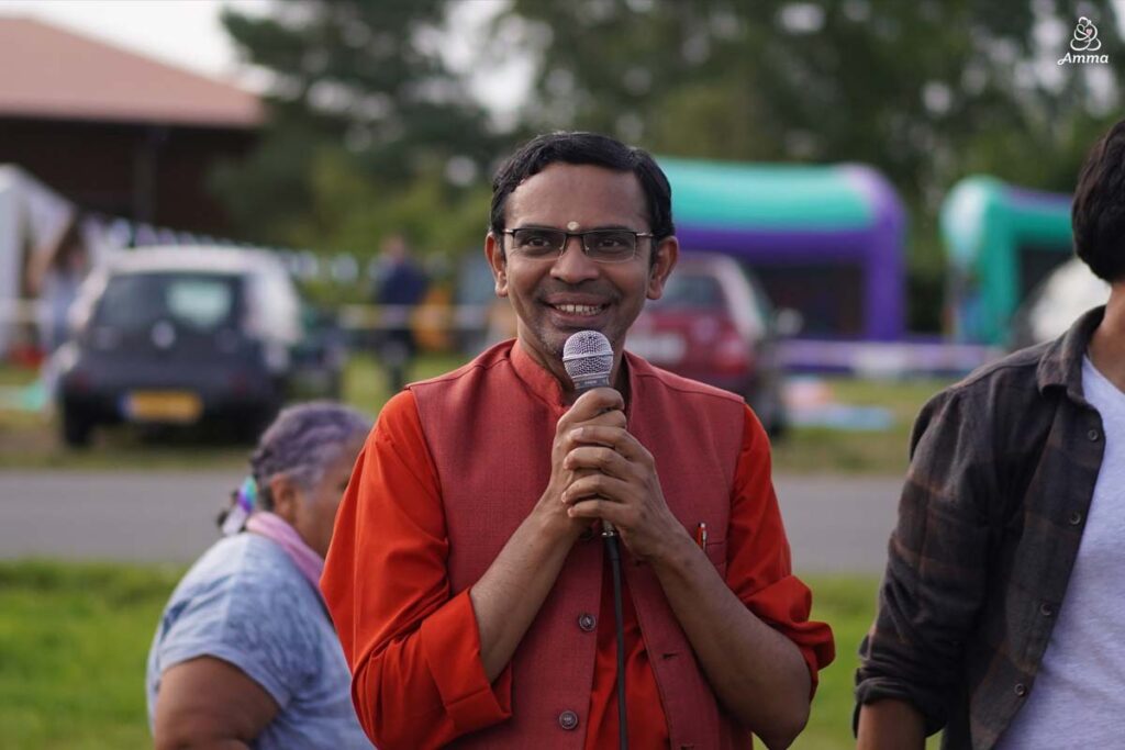 A swami holds a microphone