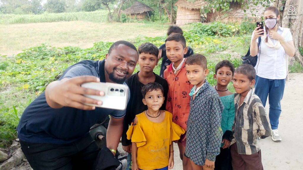 an adult takes a selfie with a group of village children