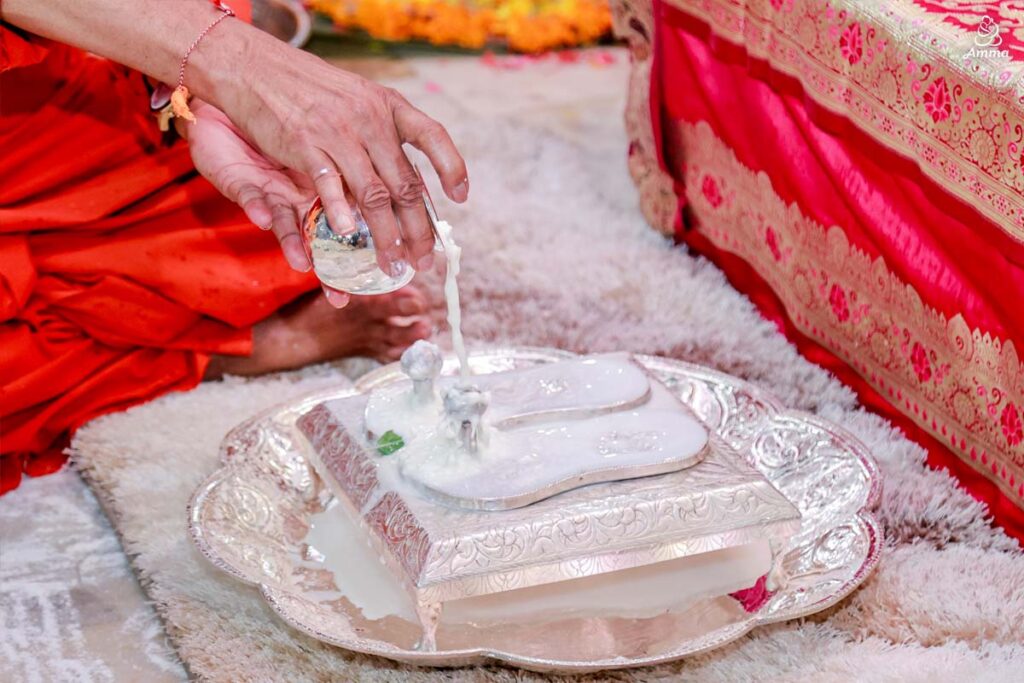 A Swami pours milk over silver sandals
