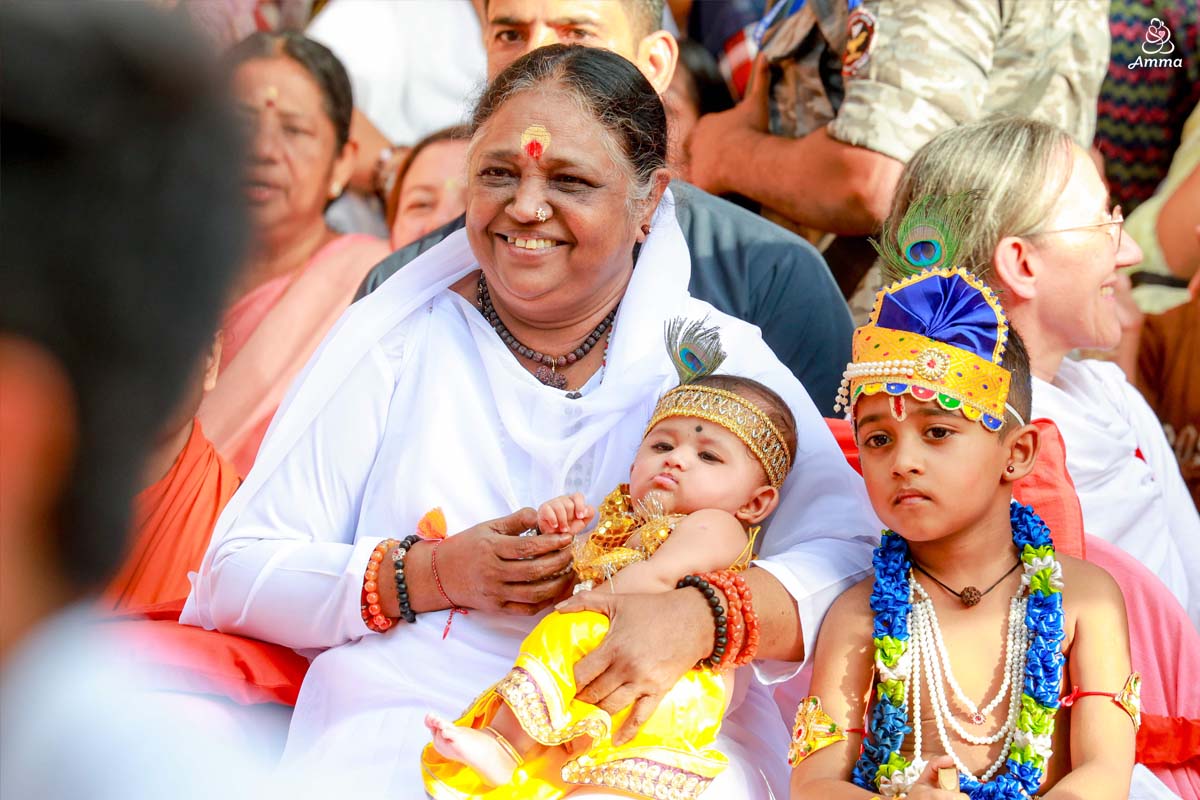 Amma holds a baby dressed as Krishna.