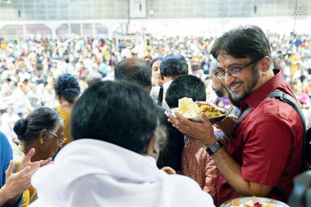 A man smiles when Amma gives him prasad