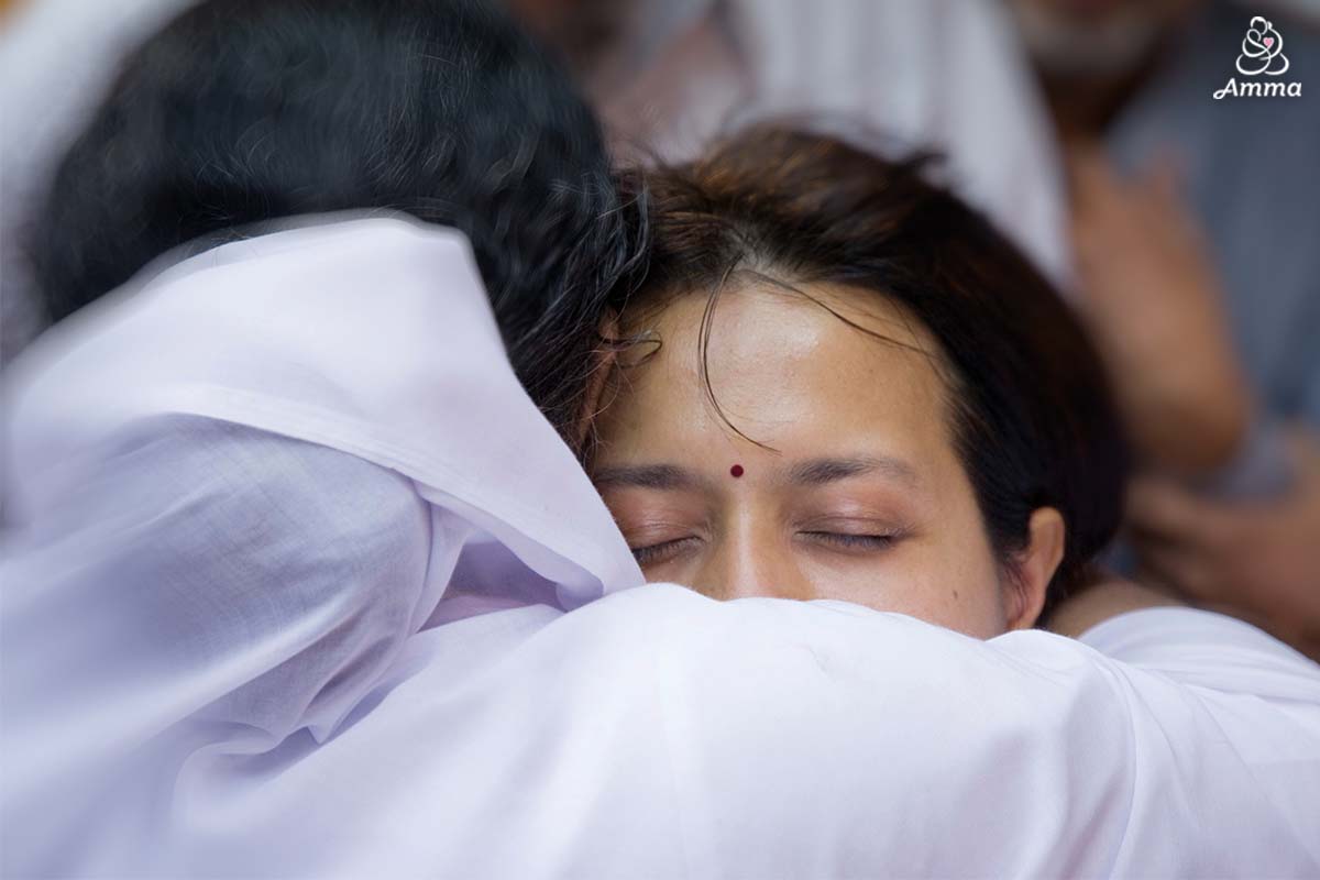 Amma from behind embracing a woman