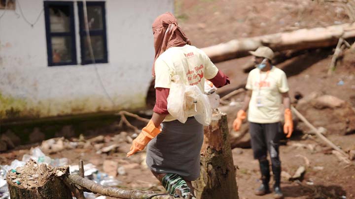 A man with a covered head walks in an area of landslide rubble