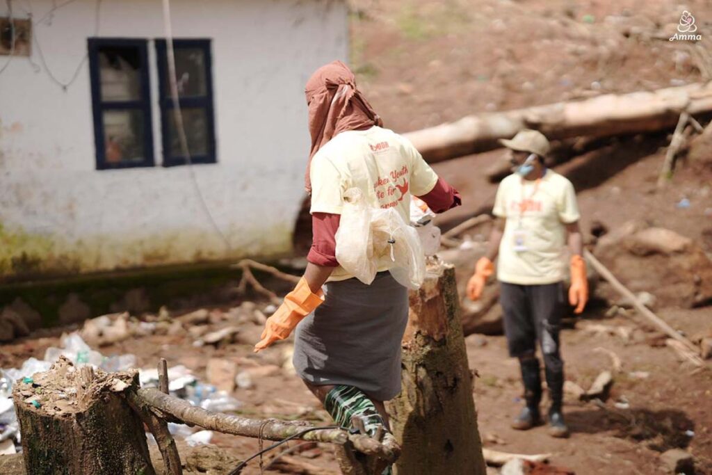 A man with a covered head walks in an area of landslide rubble