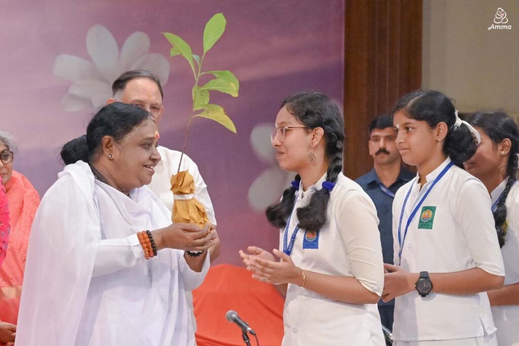 Amma gives a sapling to a young woman