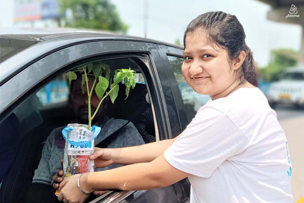 a young woman gives a sapling