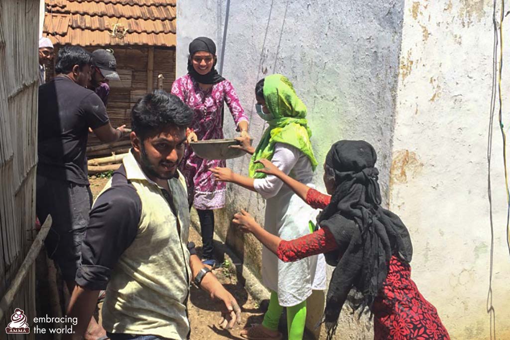 Villagers pass something in a street along with Amrita University students