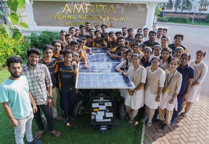 largee group of male and female pose with solar vehicles