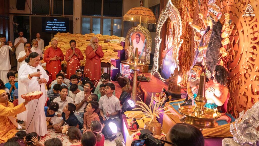 Amma throws flower petals in a puja