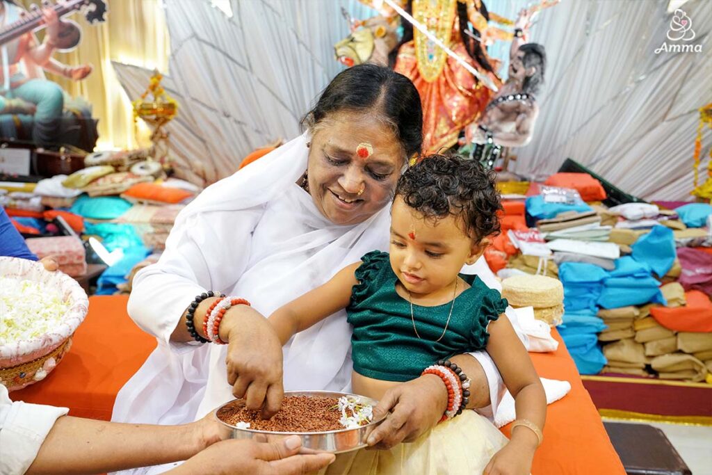 Amma performs a little girl's first writing ceremony