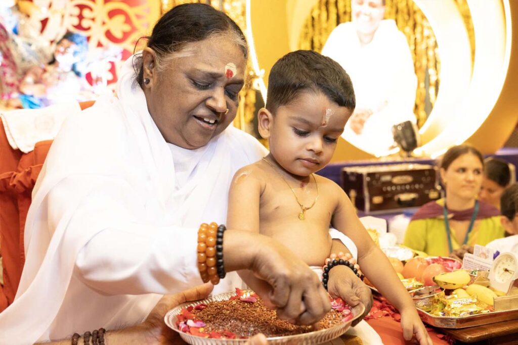 Amma introduces a child to writing
