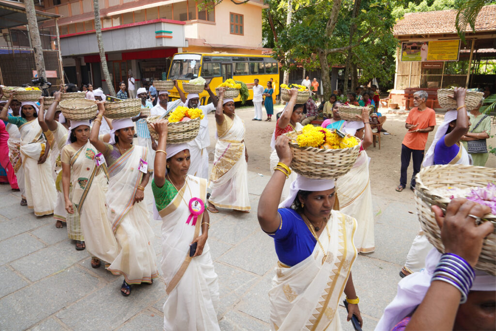 A traditional procession of women in Kerala saris carrying baskets of rice and flowers on their heads in honour of Amma.