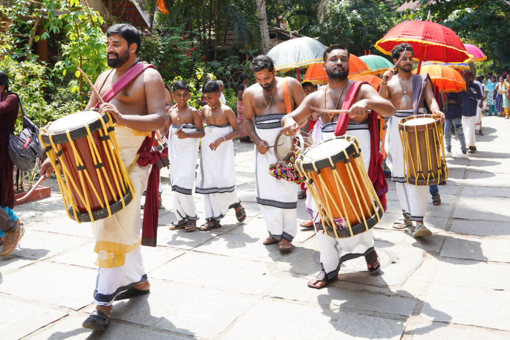 A procession of men playing the  chenda which originated in Kerala as a cylindrical percussion instrument.