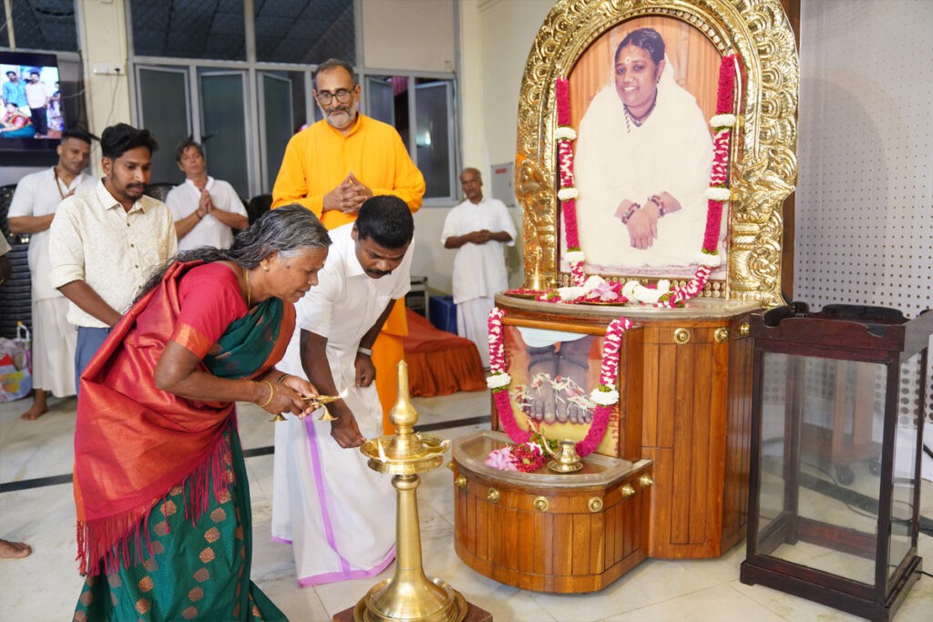 Nanjiyamma bows to light the arati lamp on stage in front of Amma's altar.