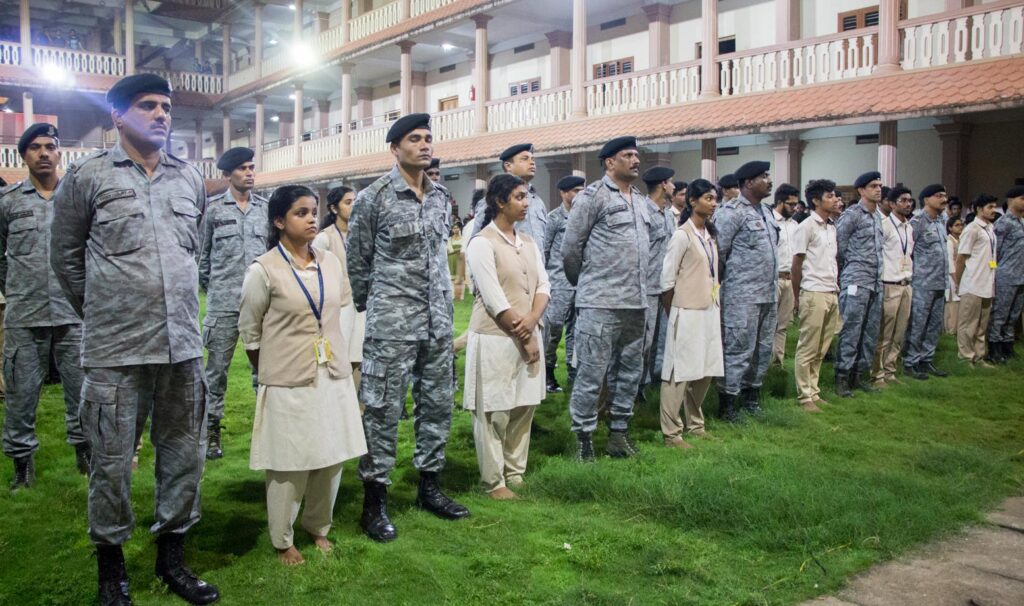 Students, Staff, and Soldiers standing on grass in the courtyard of the campus.